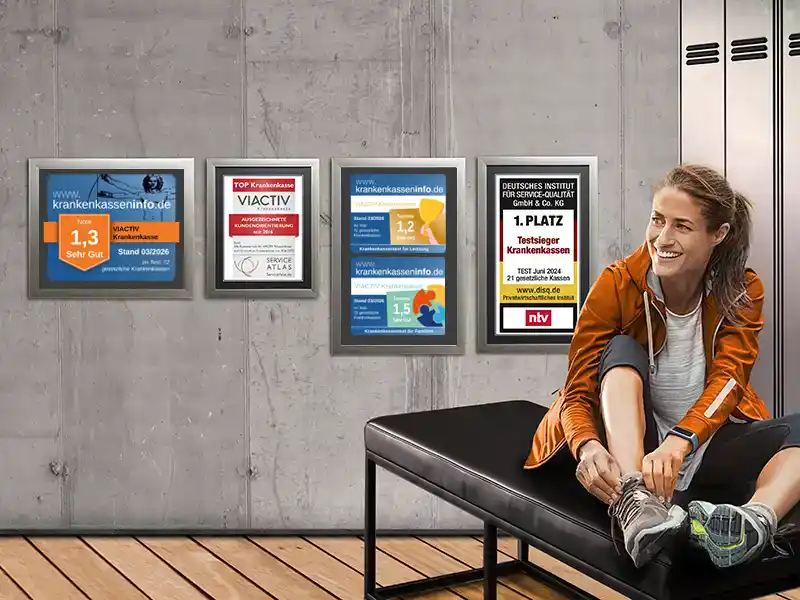 Eine Frau bindet sich ihren Sportschuh zu. Sie sitzt in der Umkleide und hinter ihr an der Wand hängen die Auszeichnungen der VIACTIV Krankenkasse. | VIACTIV Krankenkasse