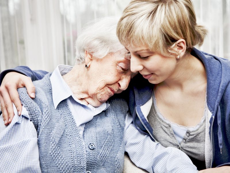 Eine jüngere Dame, die eine ältere Dame pflegt. Auch die Leistungen im Bezug auf Pflege werden oftmals von der Krankenversicherung übernommen. | VIACTIV Krankenkasse