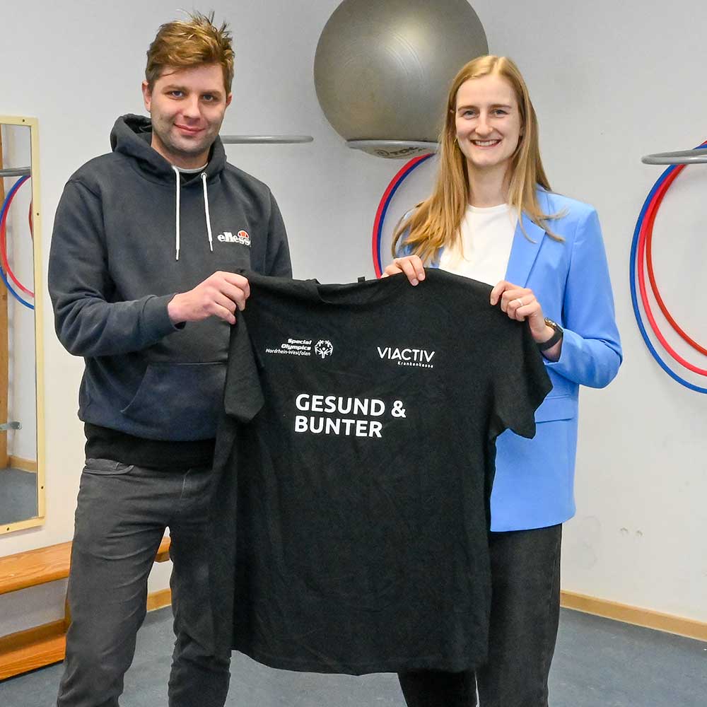 Zwei Organisatoren des Projekts "Gesund und Bunter" halten stolz ein schwarzes T-Shirt in die Kamera. | VIACTIV Krankenkasse