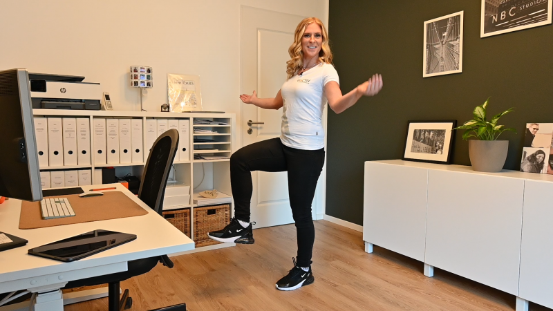 Frau im Arbeitszimmer zeigt Übung zur Stärkung der Tiefenmuskulatur. | VIACTIV Krankenkasse