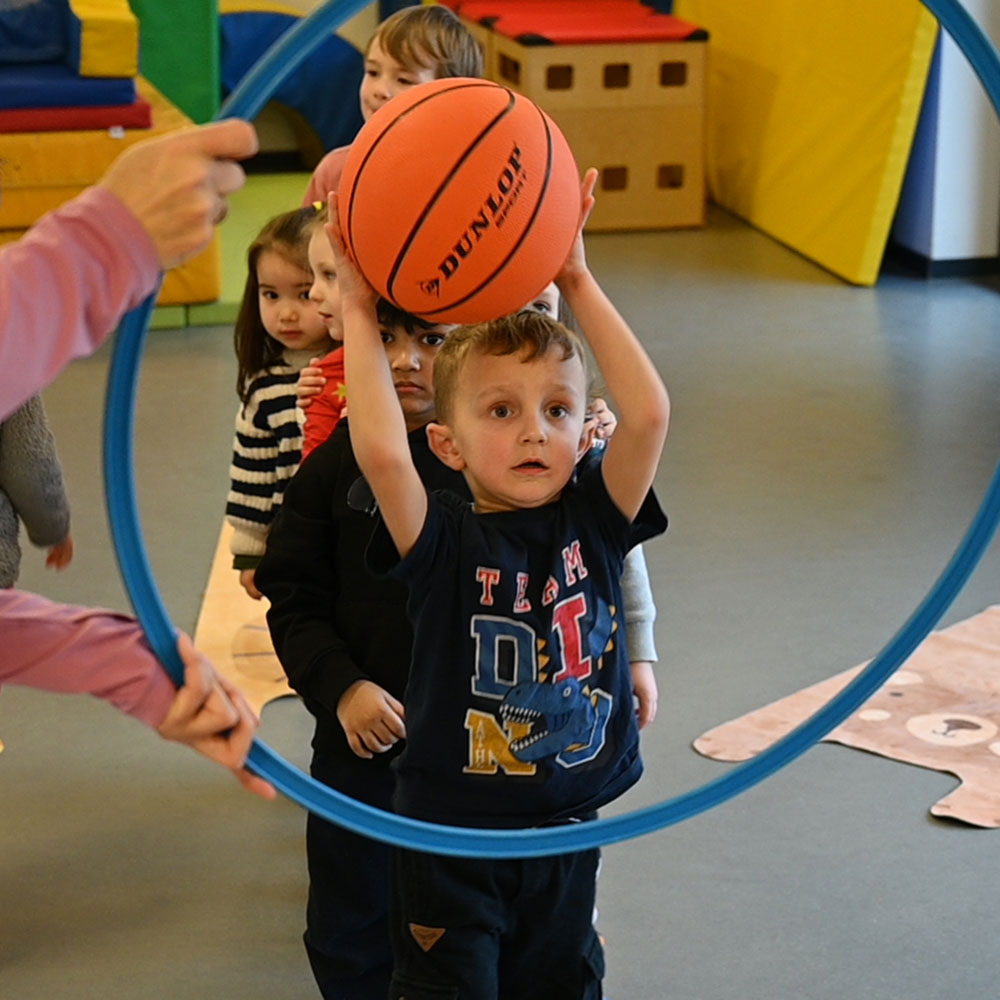 Kinder im Kindergarten spielen mit Ball und Hulahoop-Reifen. | VIACTIV Krankenkasse
