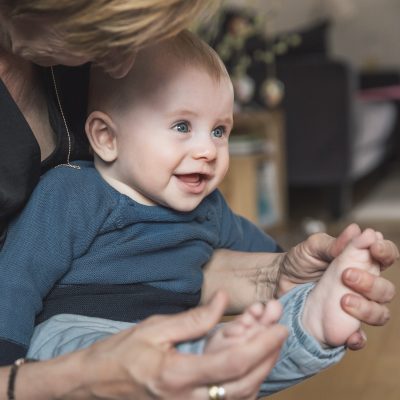 Woman playing with baby boys feet at home | VIACTIV Krankenkasse
