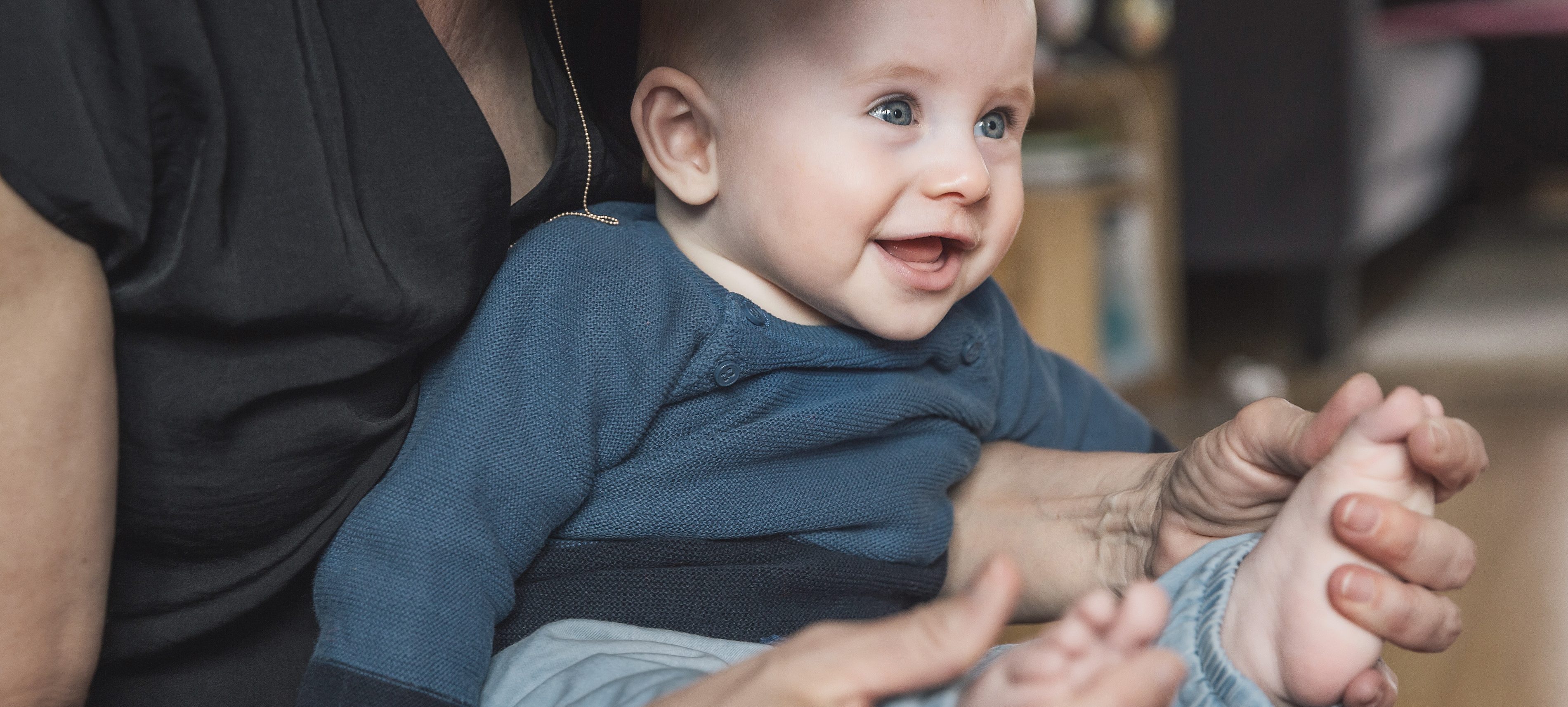 Woman playing with baby boys feet at home | VIACTIV Krankenkasse