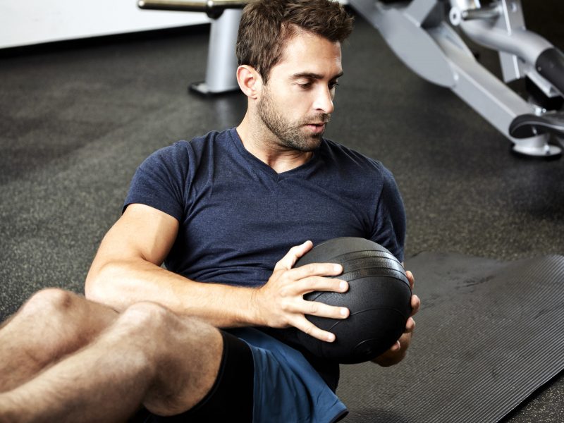 Ein junger Mann trainiert im Fitness-Studio mit einem Medizinball. | VIACTIV Krankenkasse