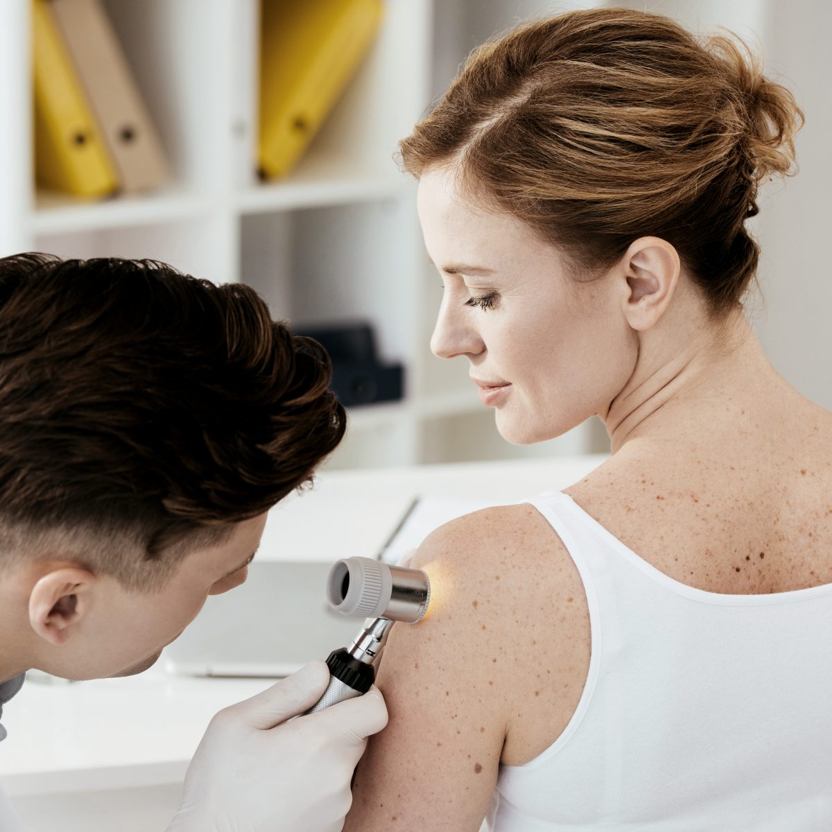 Ein Arzt führt eine Auflichtmikroskopie bei der Patientin am Arm durch. | VIACTIV Krankenkasse