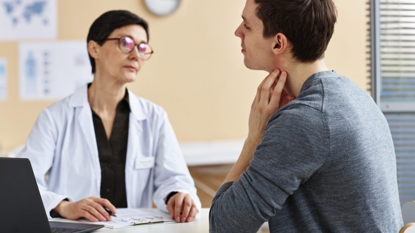 Ein Mann kratzt sich aufgrund einer Allergie beim Arzt am Hals. | VIACTIV Krankenkasse