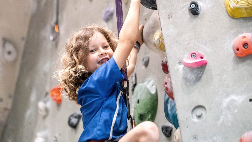 Ein jüngeres Kind hängt an der Boulderwand. | VIACTIV Krankenkasse