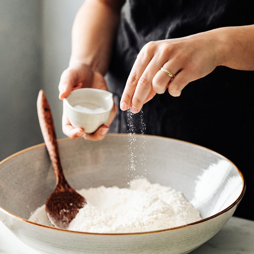 Woman sprinkling salt in flour before mixing | VIACTIV Krankenkasse