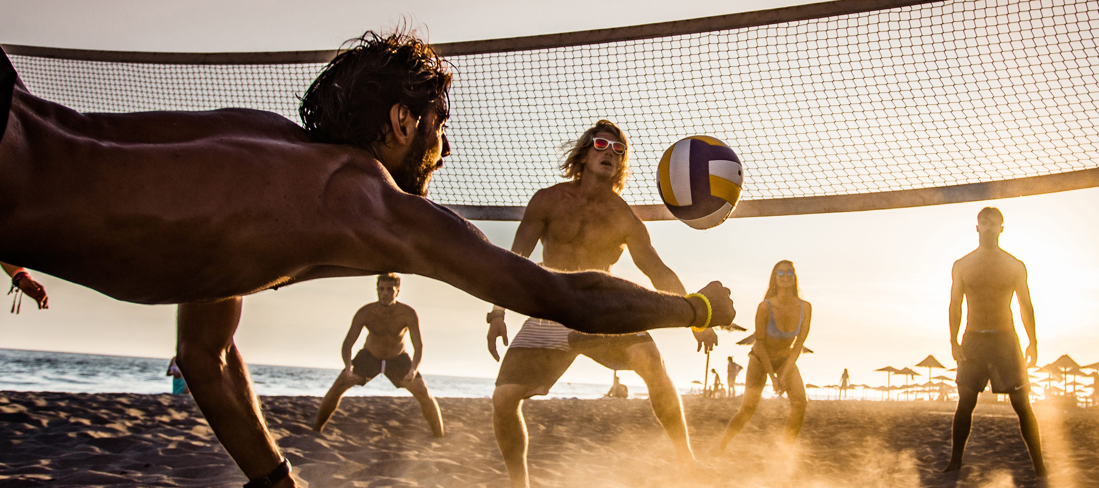 Eine Gruppe Menschen spielt Beachvolleyball in der Sonne. | VIACTIV Krankenkasse