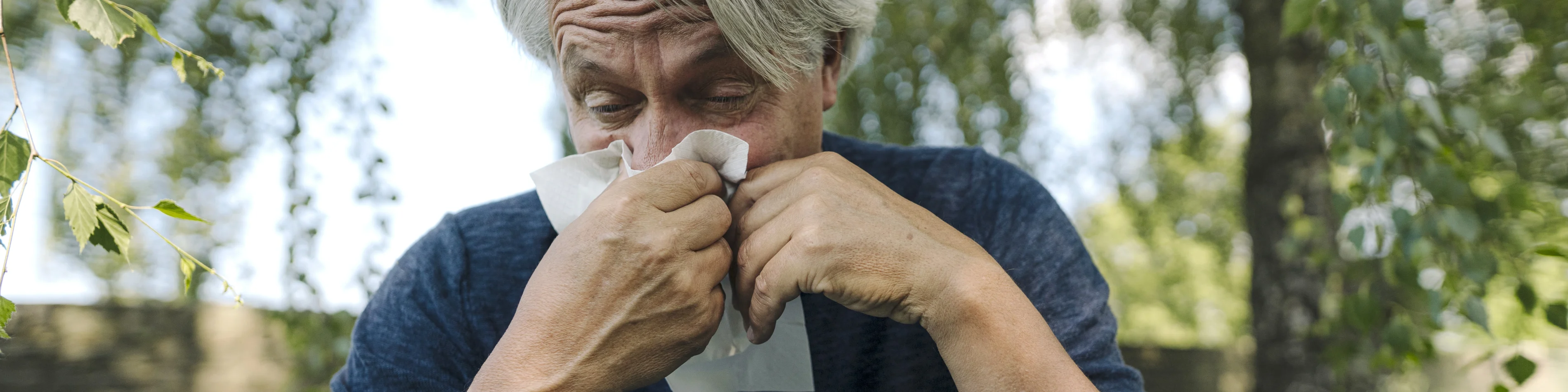 Ein älterer Mann putzt sich die Nase aufgrund einer Allergie. | VIACTIV Krankenkasse