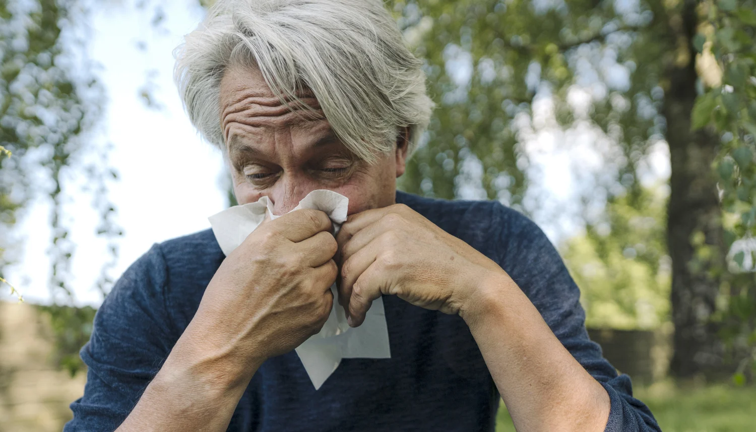 Ein älterer Mann putzt sich die Nase aufgrund einer Allergie. | VIACTIV Krankenkasse