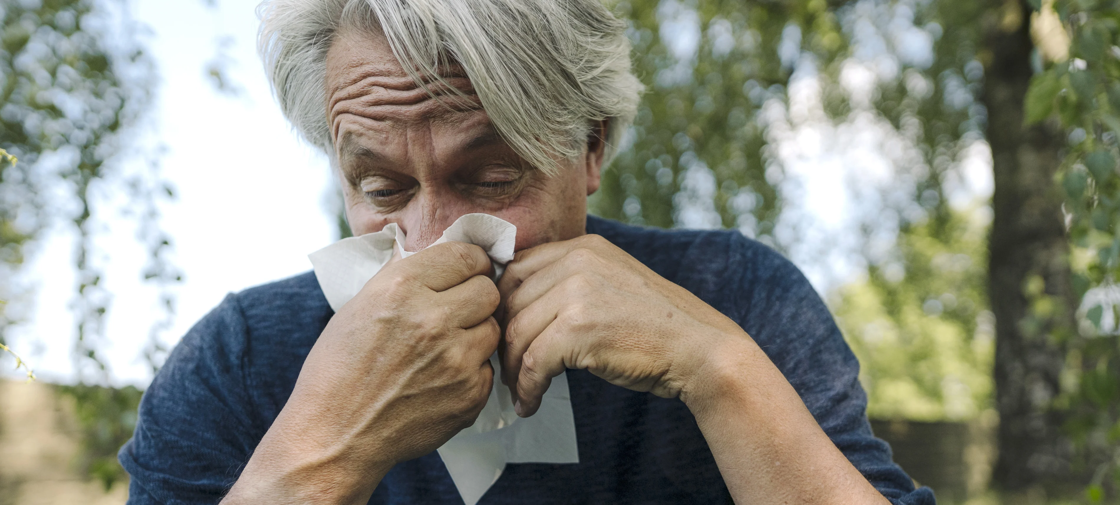Ein älterer Mann putzt sich die Nase aufgrund einer Allergie. | VIACTIV Krankenkasse