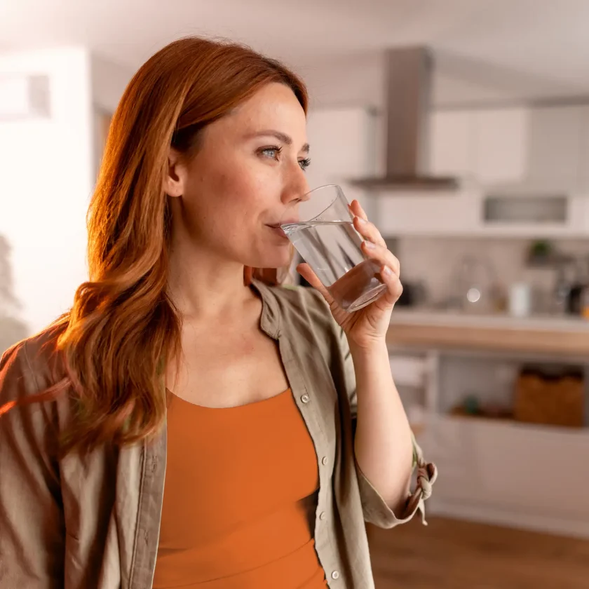 Eine junge Frau trinkt ein Glas Wasser. | VIACTIV Krankenkasse