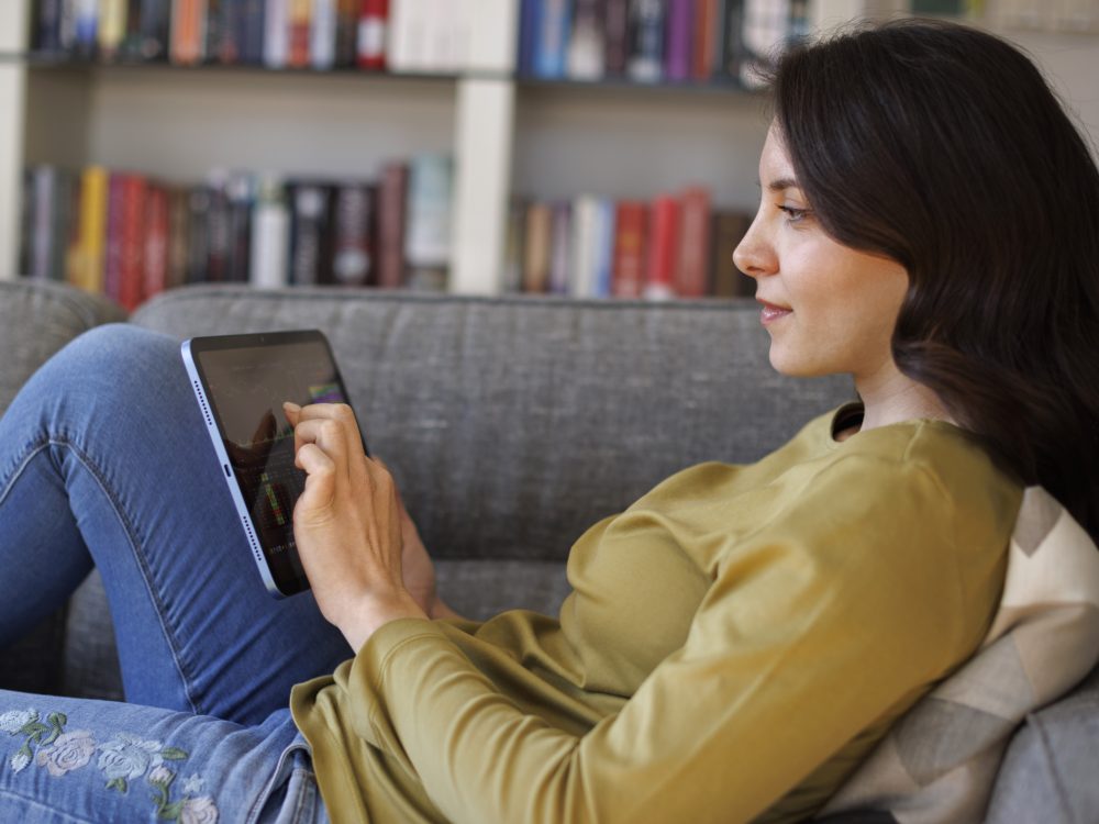 Young woman checking stock market chart on digital tablet at home | VIACTIV Krankenkasse