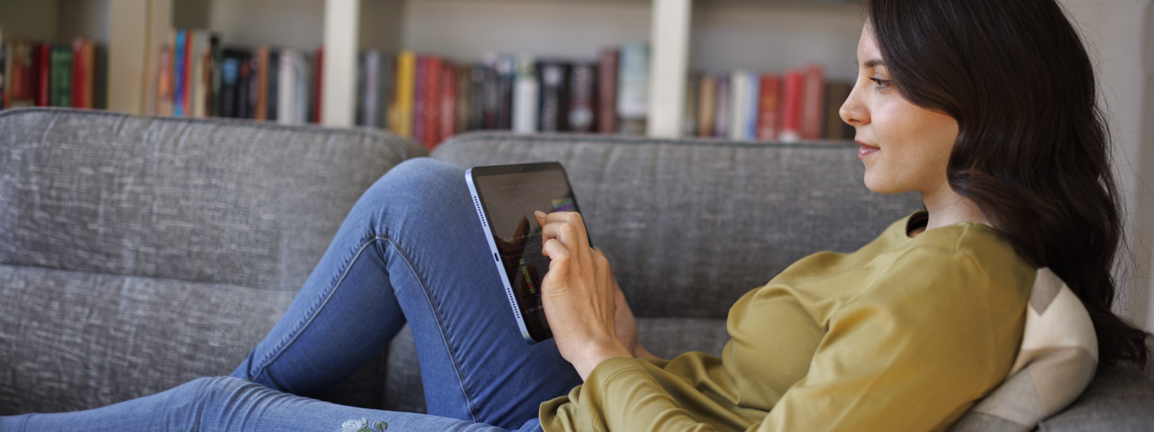 Young woman checking stock market chart on digital tablet at home | VIACTIV Krankenkasse