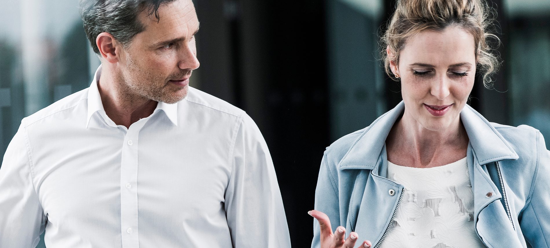 Businesswoman and businessman talking in office passageway | VIACTIV Krankenkasse