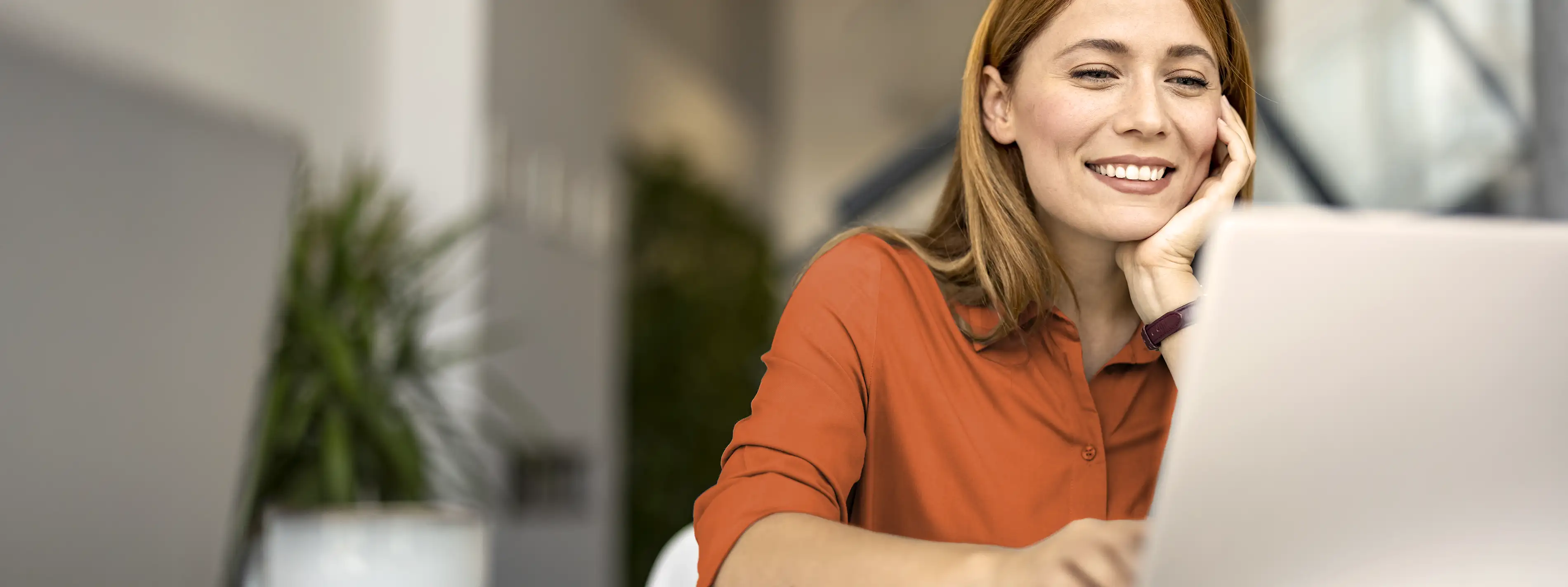 Eine Frau sitzt vor dem Laptop und schaut sich interessiert etwas an. | VIACTIV Krankenkasse