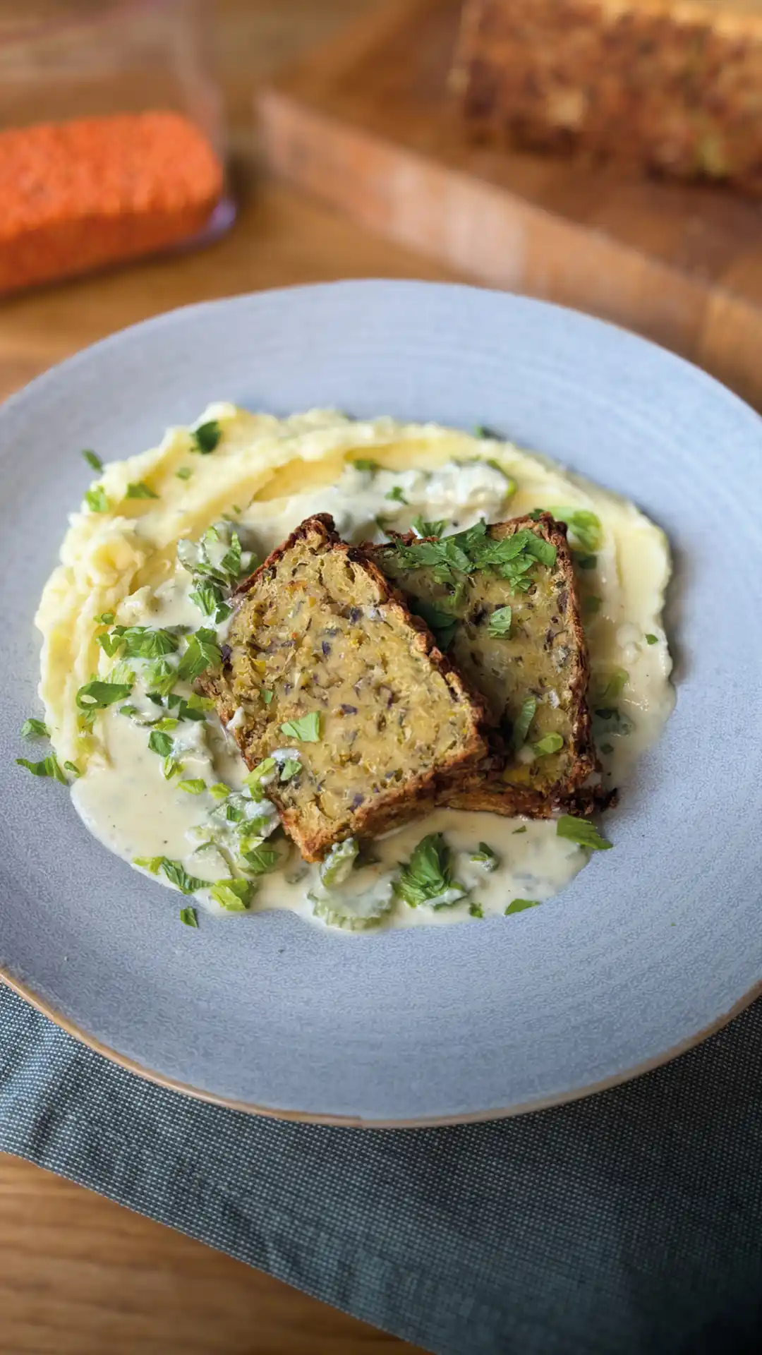Linsenbraten mit Gorgonzola-Soße auf Kartoffelpüree auf einem hellblauen Teller. | VIACTIV Krankenkasse