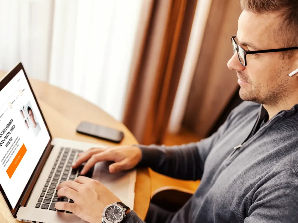 Ein Mann sitzt am Tisch und hat dort einen Laptop und ein Smartphone liegen. | VIACTIV Krankenkasse