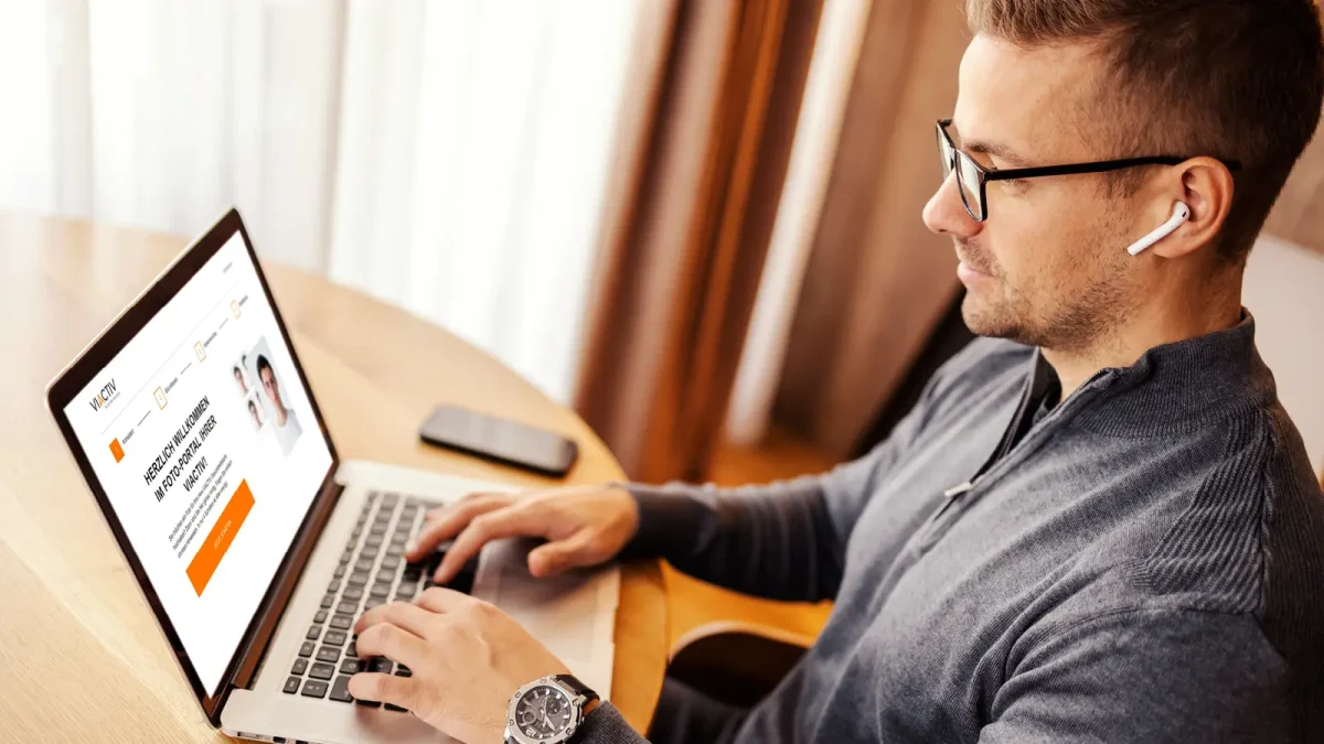 Ein Mann sitzt am Tisch und hat dort einen Laptop und ein Smartphone liegen. | VIACTIV Krankenkasse