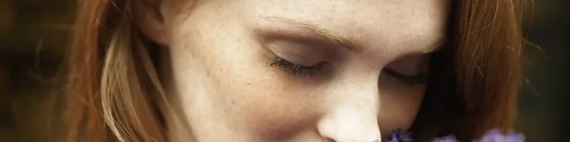 Eine Frau mit rötlichen Haaren riecht an einem Strauß Lavendel und hat die Augen geschlossen. | VIACTIV Krankenkasse