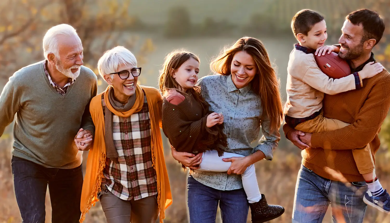 Eine sechsköpfige Familie geht gemeinsam durch die Natur. Es herbstlich aus. | VIACTIV Krankenkasse