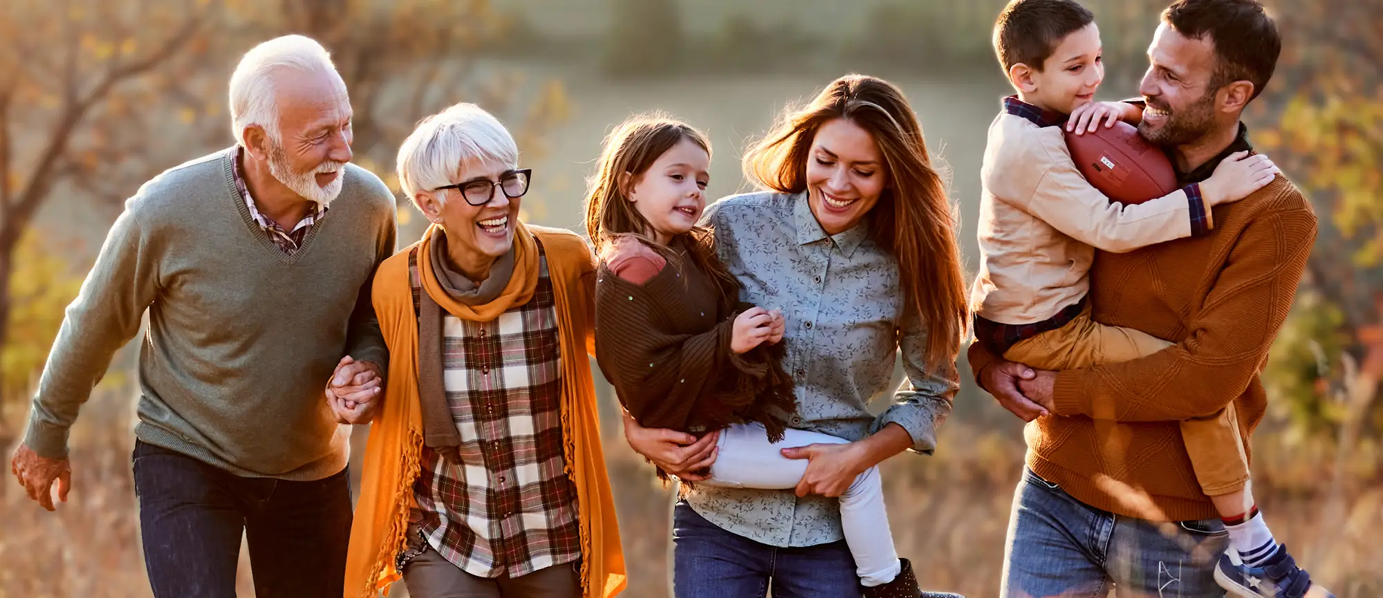 Eine sechsköpfige Familie geht gemeinsam durch die Natur. Es herbstlich aus. | VIACTIV Krankenkasse