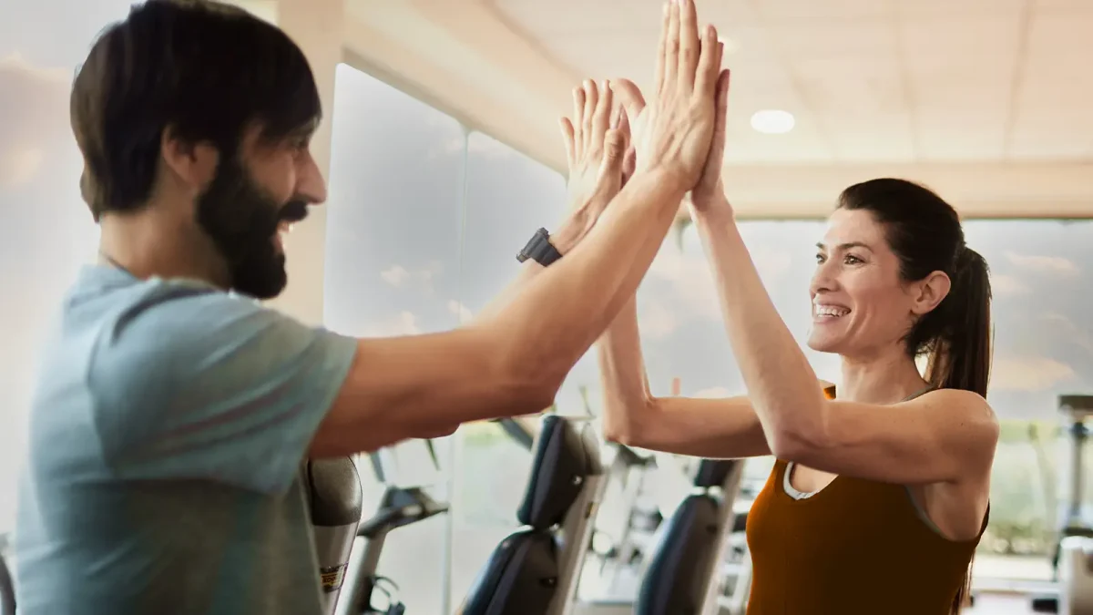 Ein Mann und eine Frau klatschen sich im Fitnessstudio mit den Händen ab. | VIACTIV Krankenkasse