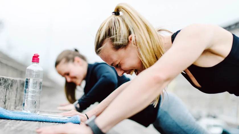 Zwei Frauen treiben draußen Sport und machen aktuell Liegestütze an einer Betontreppe. | VIACTIV Krankenkasse
