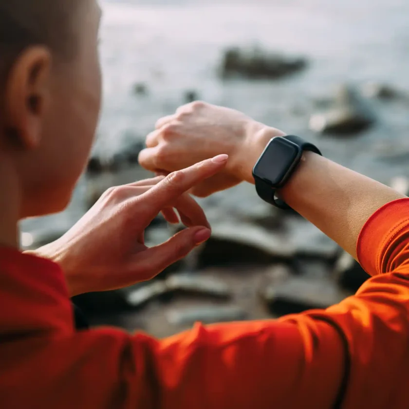 Eine Frau tippt mit ihrem linken Zeigefinger auf eine Smartwatch. Diese trägt sie am rechten Handgelenk. | VIACTIV Krankenkasse