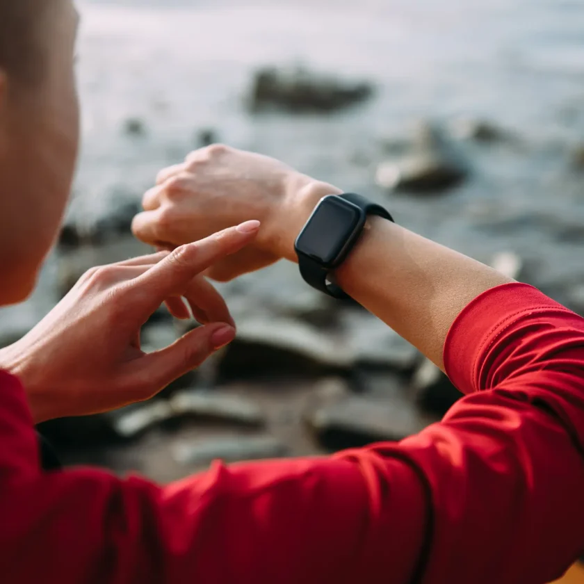 Eine Frau tippt mit ihrem linken Zeigefinger auf eine Smartwatch. Diese trägt sie am rechten Handgelenk. | VIACTIV Krankenkasse