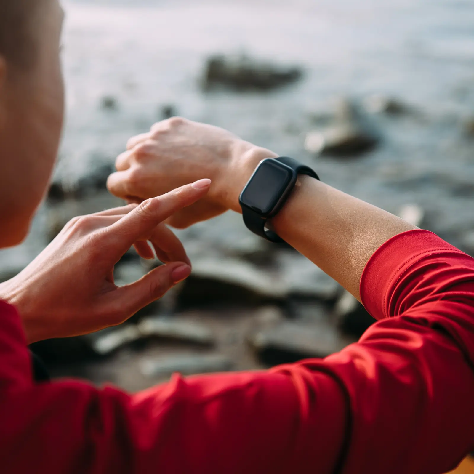 Eine Frau tippt mit ihrem linken Zeigefinger auf eine Smartwatch. Diese trägt sie am rechten Handgelenk. | VIACTIV Krankenkasse