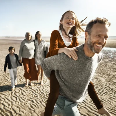 Eine Familie macht einen Ausflug am Strand. Sie sehen glücklich aus. | VIACTIV Krankenkasse