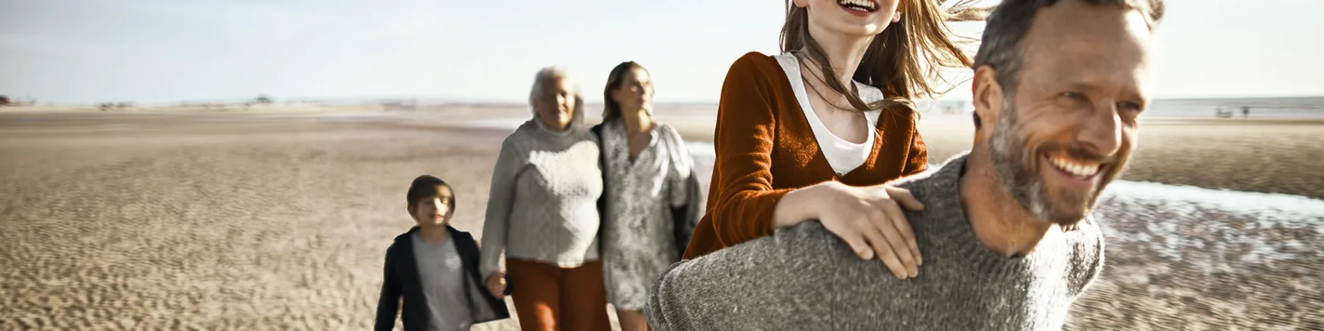 Eine Familie macht einen Ausflug am Strand. Sie sehen glücklich aus. | VIACTIV Krankenkasse