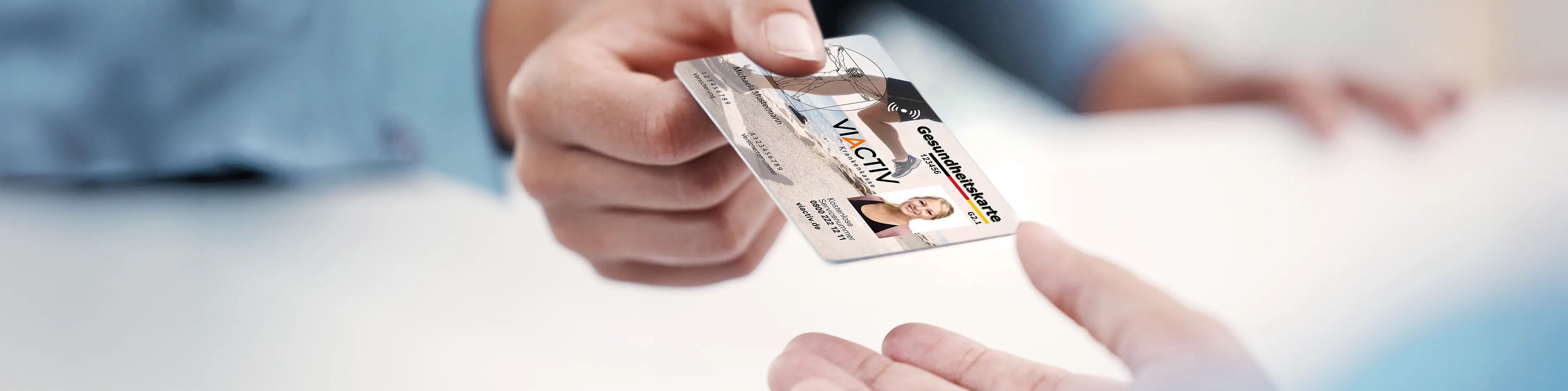 Nahaufnahme einer Hand, die eine elektronische Gesundheitskarte an eine weitere Person übergibt. | VIACTIV Krankenkasse