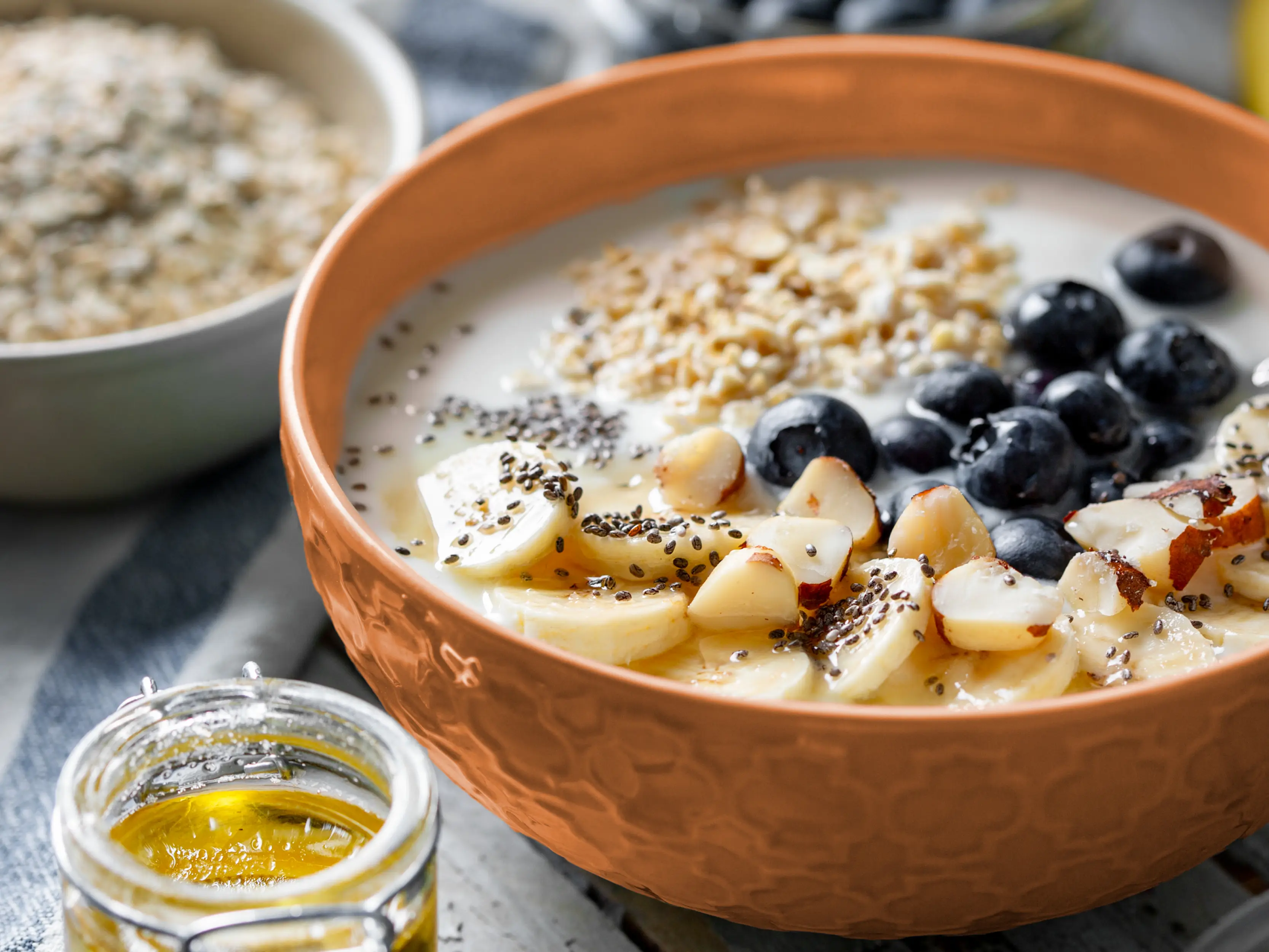 Eine Frühstücksbowl aus Haferflocken, Chiasamen und frischem Obst in einer Holzschale. | VIACTIV Krankenkasse