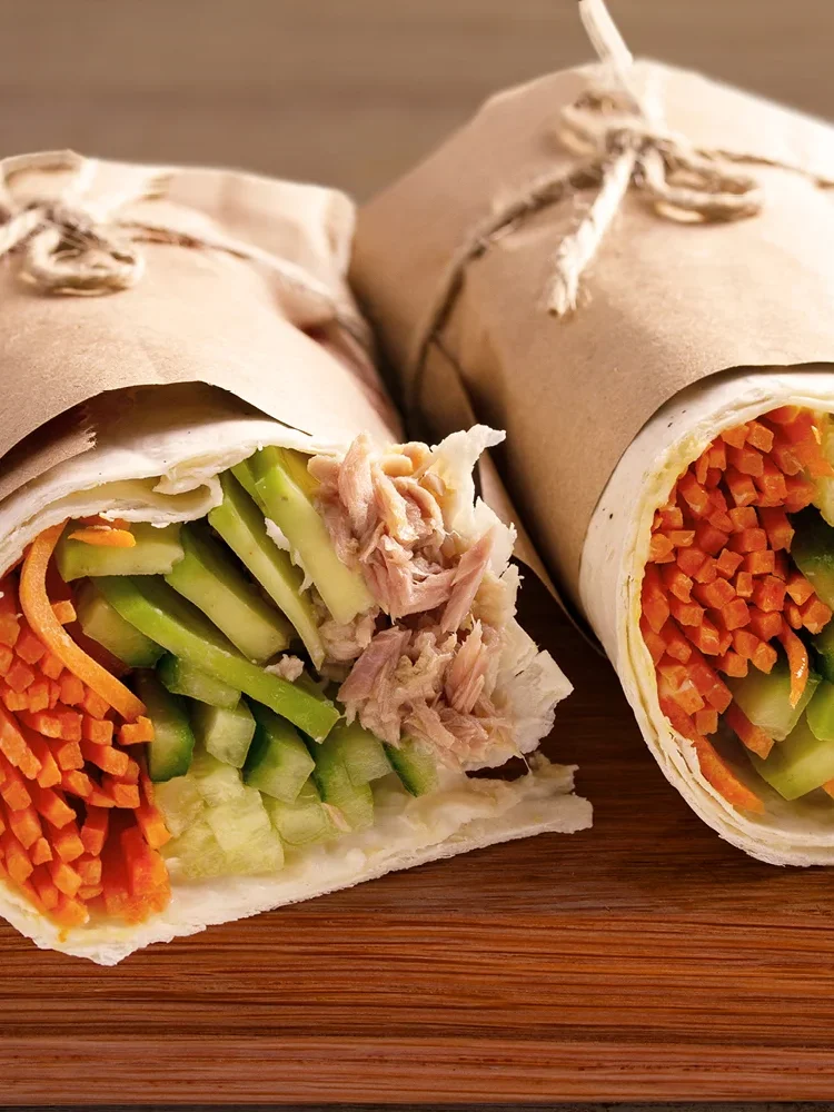 Zwei Wraps mit Möhre, Gurke und Thunfisch in braunem Papier. | VIACTIV Krankenkasse