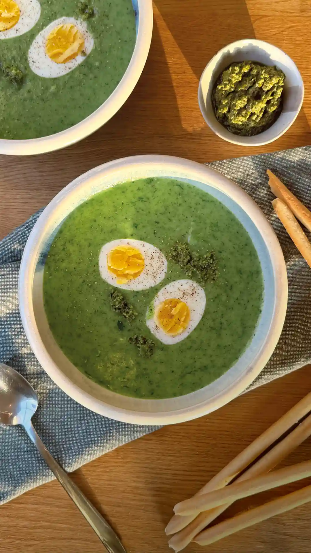 Eine grüne Bärlauchcremesuppe, garniert mit einem gekochten Ei in einer weißen Suppenschale. | VIACTIV Krankenkasse