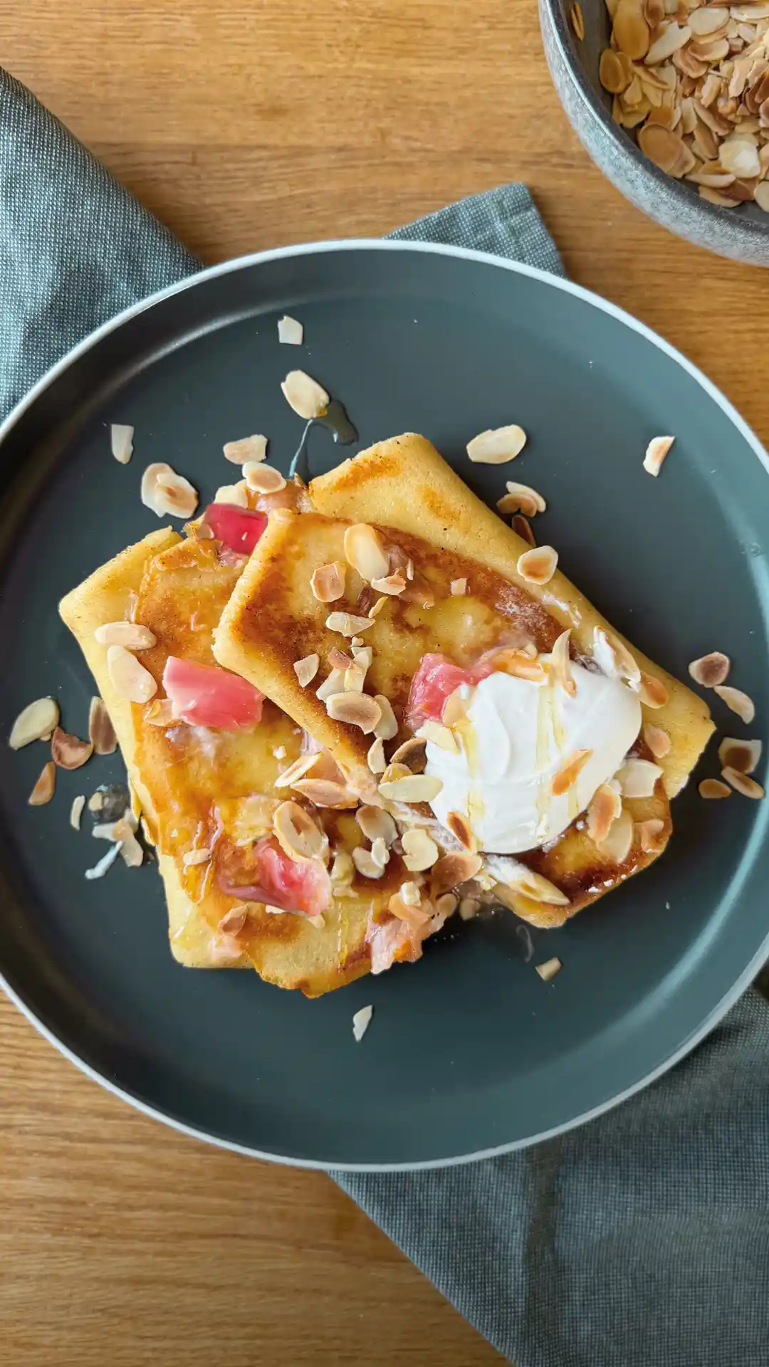 Zwei Pfannkuchen garniert mit Rhabarber auf einem dunkelblauen Teller. | VIACTIV Krankenkasse