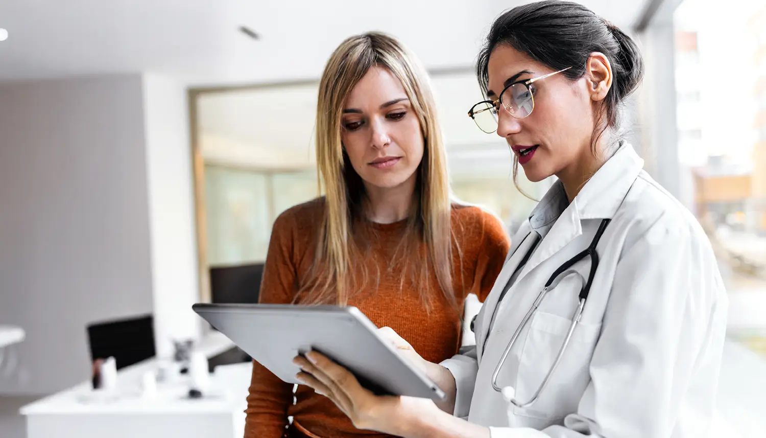 Eine Ärztin berät ihre Patienten. Beide schauen sich etwas auf dem Tablet an. | VIACTIV Krankenkasse