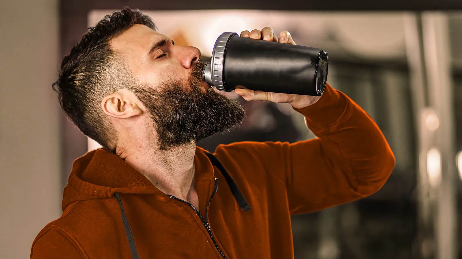Ein Mann trinkt mit geschlossenen Augen aus einer Sportflasche. | VIACTIV Krankenkasse