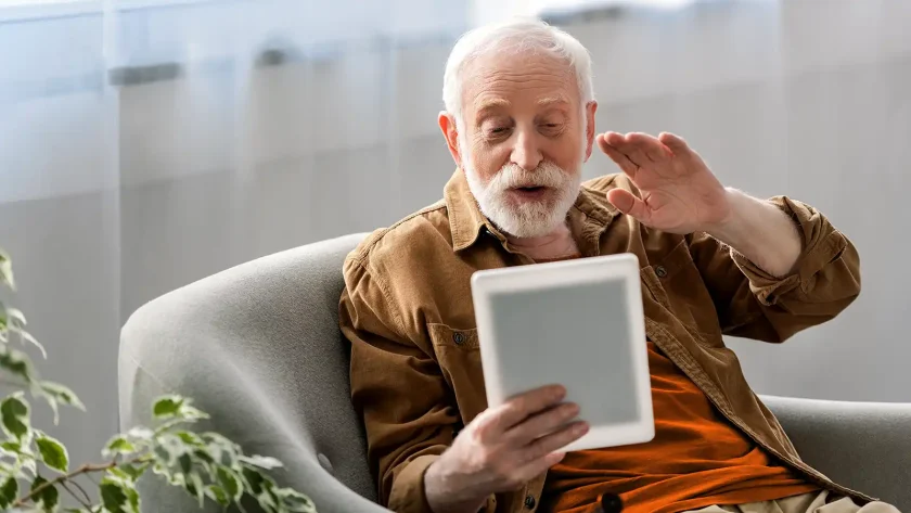 Ein älterer Mann sitzt in einem Sessel und beschäftigt sich mit dem Notebook. | VIACTIV Krankenkasse