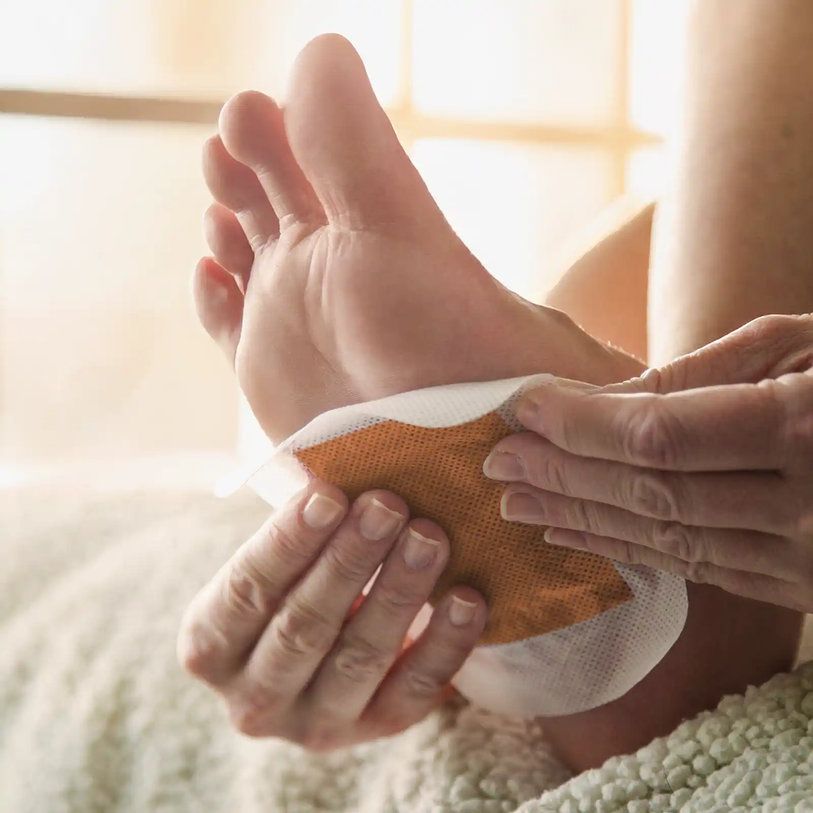 Eine Person klebt sich ein Entgiftungspflaster unter den Fuß. | VIACTIV Krankenkasse