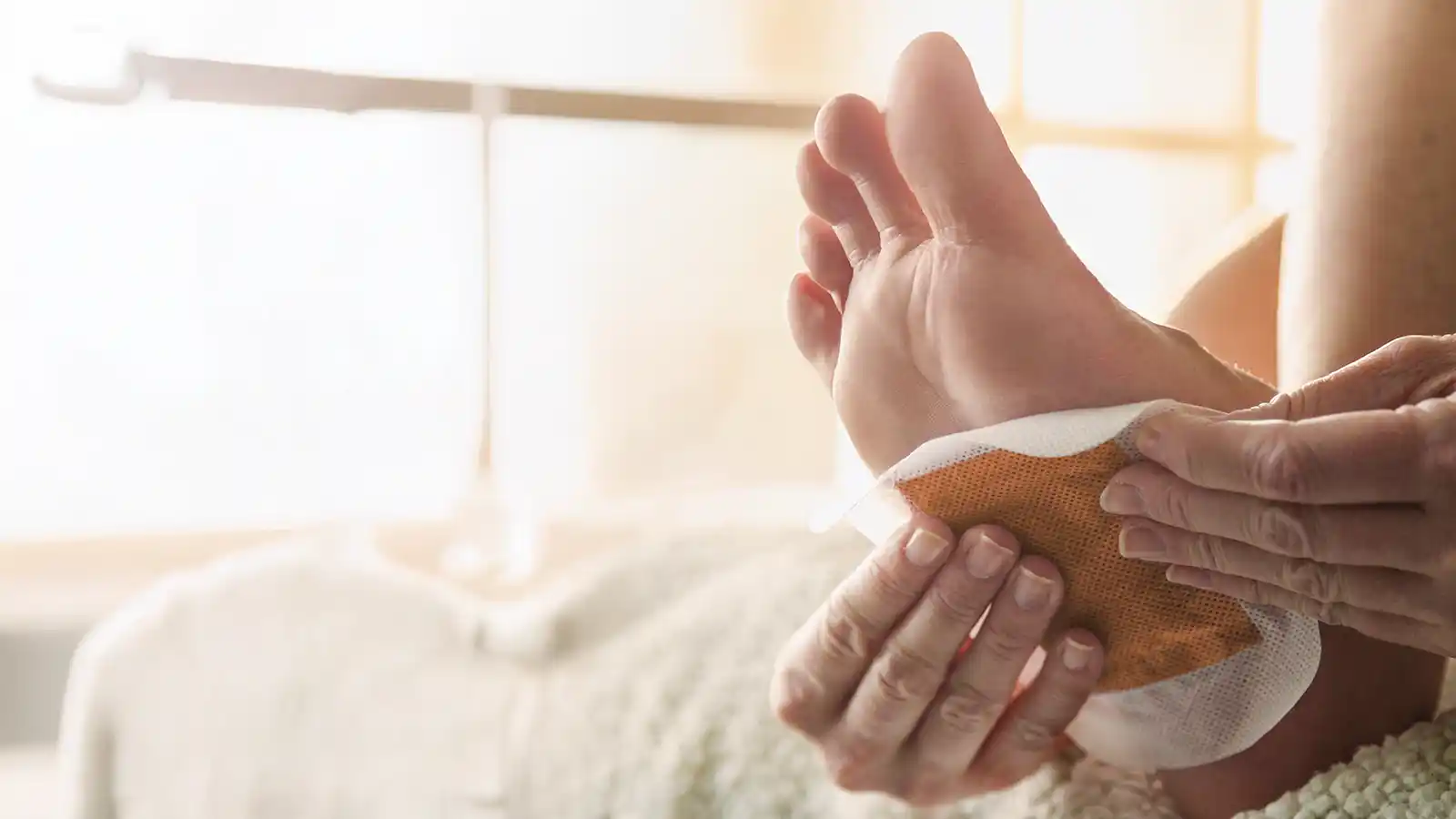 Eine Person klebt sich ein Entgiftungspflaster unter den Fuß. | VIACTIV Krankenkasse