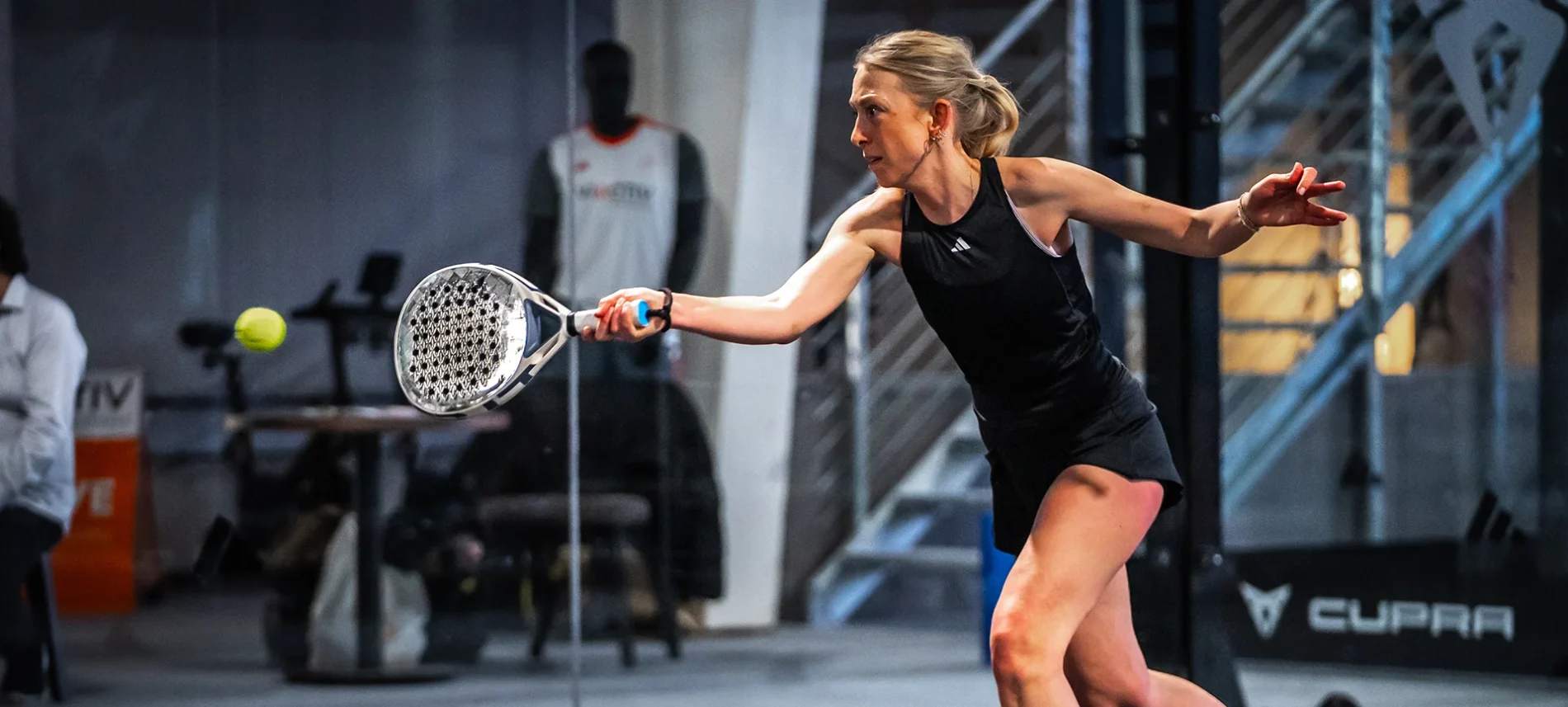 Eine Frau beim Padel-Tennis spielen auf einem Tennisplatz, die einen Schlag ausführt. | VIACTIV Krankenkasse