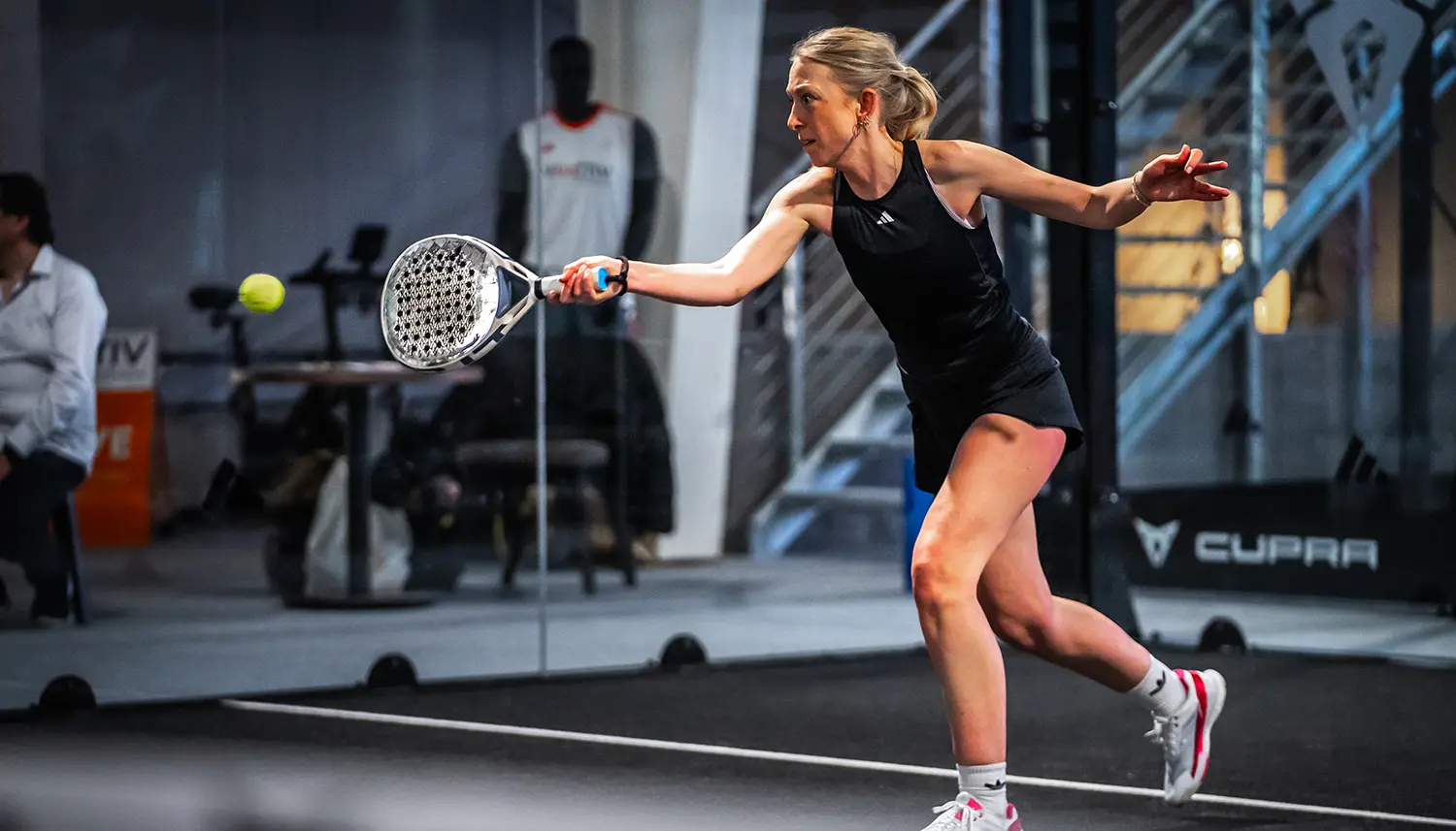 Eine Frau beim Padel-Tennis spielen auf einem Tennisplatz, die einen Schlag ausführt. | VIACTIV Krankenkasse