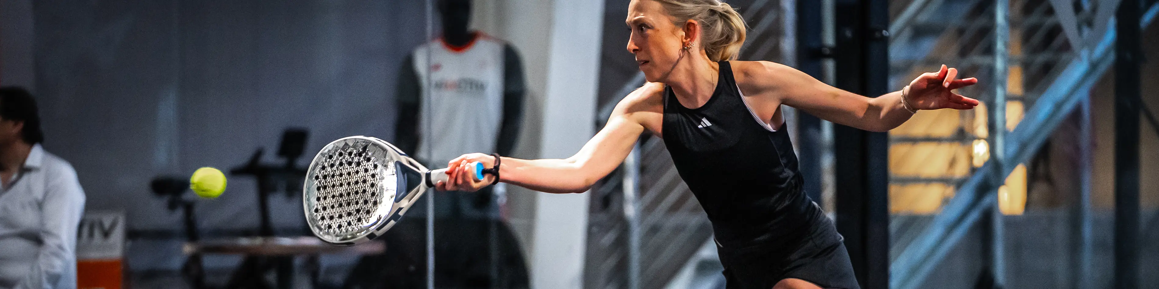 Eine Frau beim Padel-Tennis spielen auf einem Tennisplatz, die einen Schlag ausführt. | VIACTIV Krankenkasse
