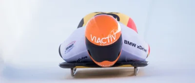 Der Skeleton-Pilot Felix Keisinger fährt bäuchlings auf dem Rodelschlitten durch den Eiskanal. Er trägt den orangenen VIACTIV-Helm. | VIACTIV Krankenkasse