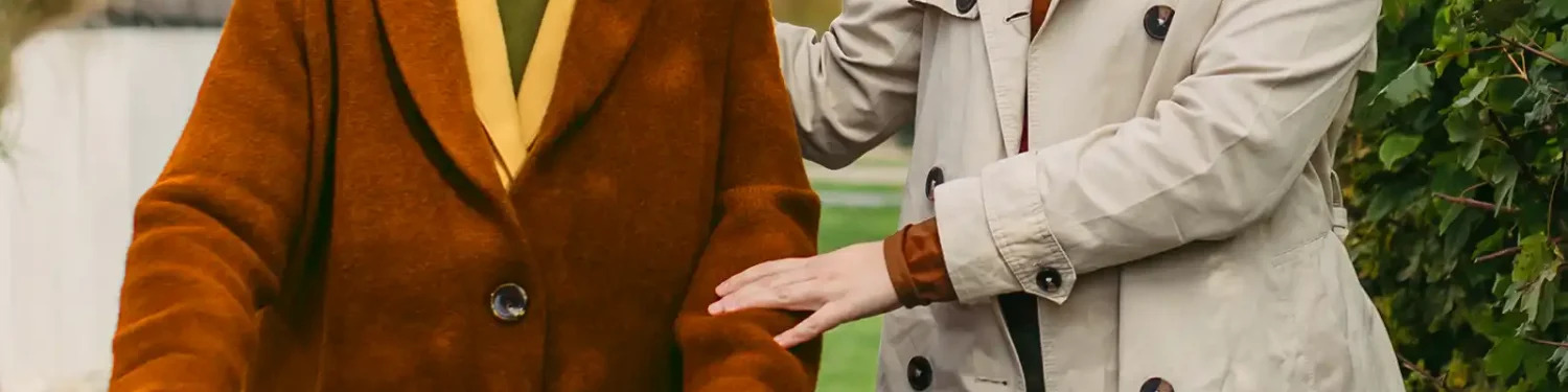 Eine ältere Frau mit einem Rollator wird auf einem Spaziergang begleitet von einer jüngeren Frau. | VIACTIV Krankenkasse