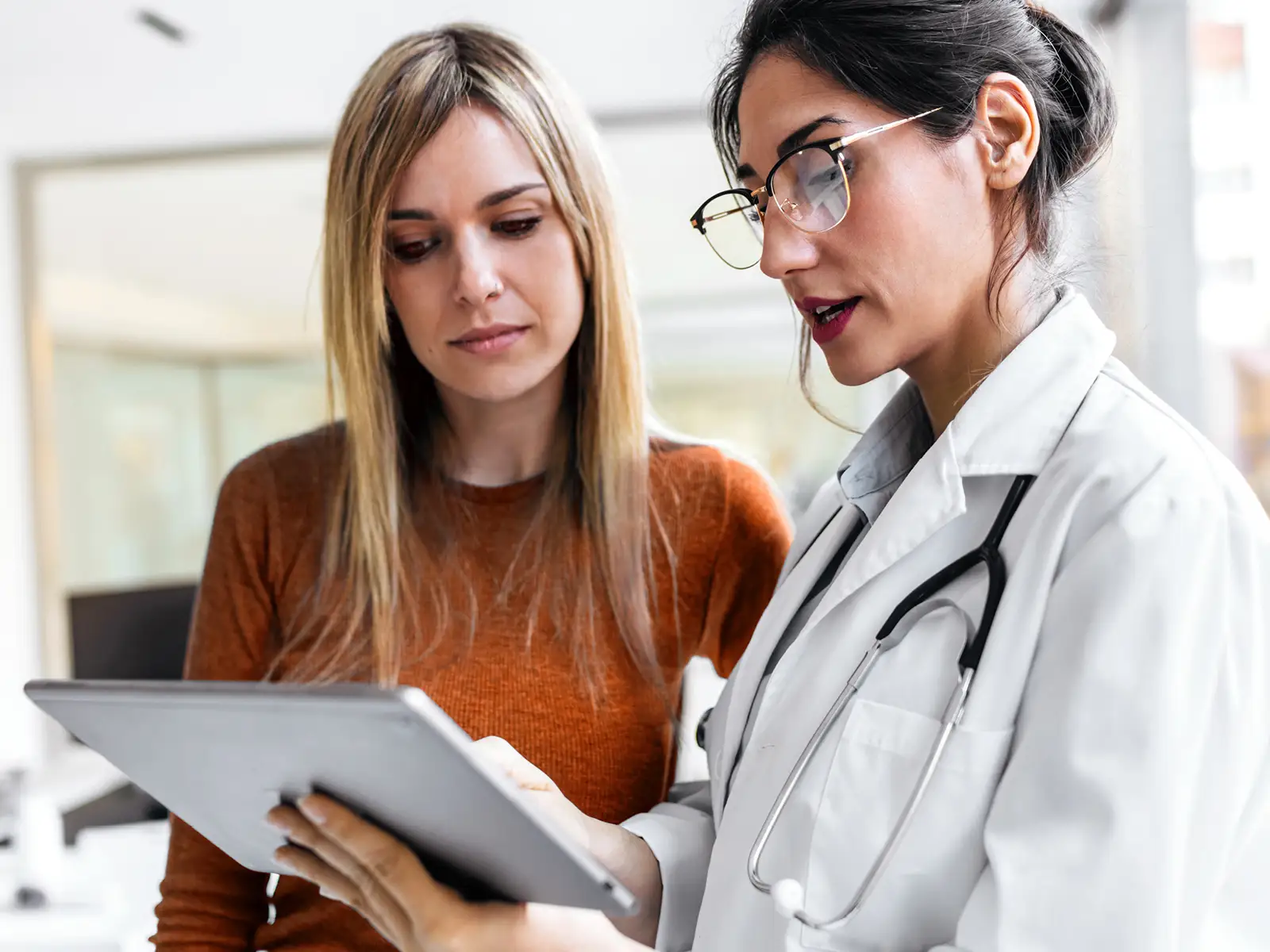 Eine Ärztin berät ihre Patienten. Beide schauen sich etwas auf dem Tablet an. | VIACTIV Krankenkasse